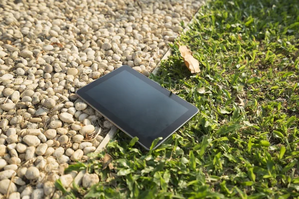 Digital tablet on grass and stone