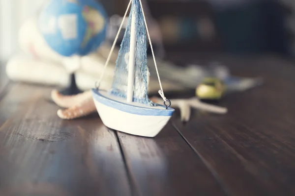 Globe, ship and car figurine, map, starfish on wooden table for