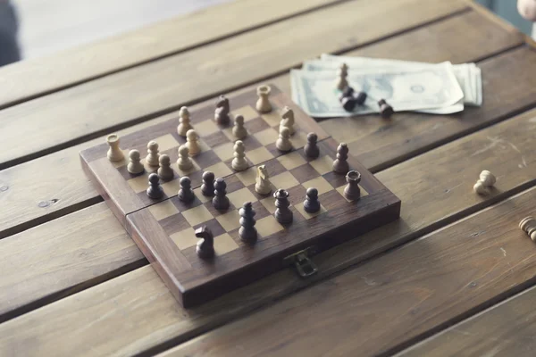 Pawn, chessboard game and banknote on wooden table, vintage tone