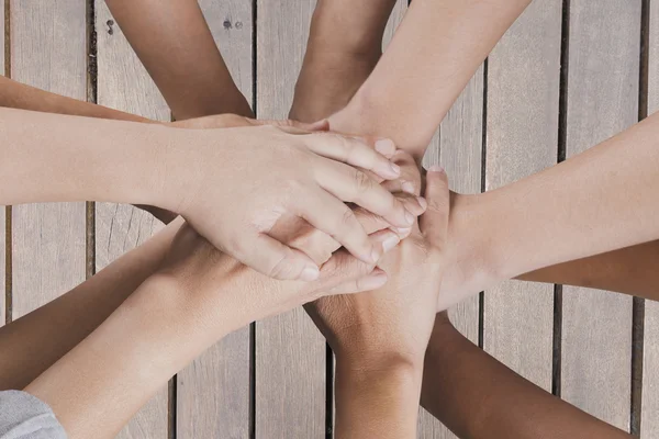 People put hand together on wooden table for use as teamwork con