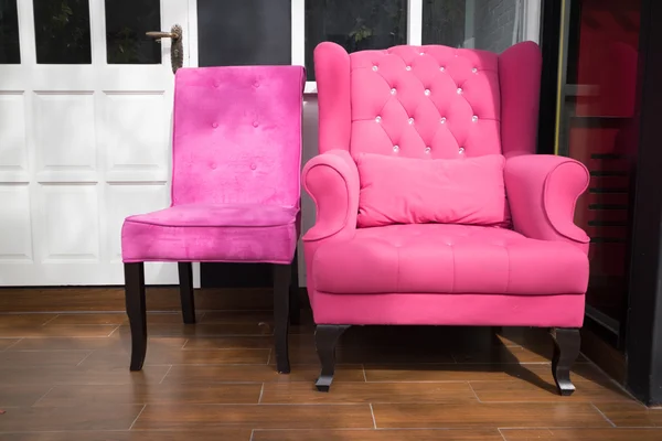 Pink fabric armchair beside white door