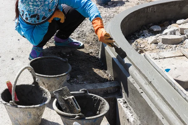 The worker apply cement over the surface of footpath edge