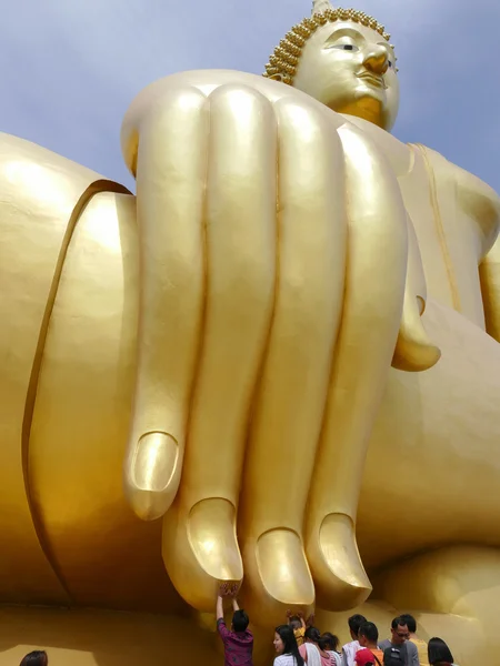 People touch finger of the big golden buddha statue