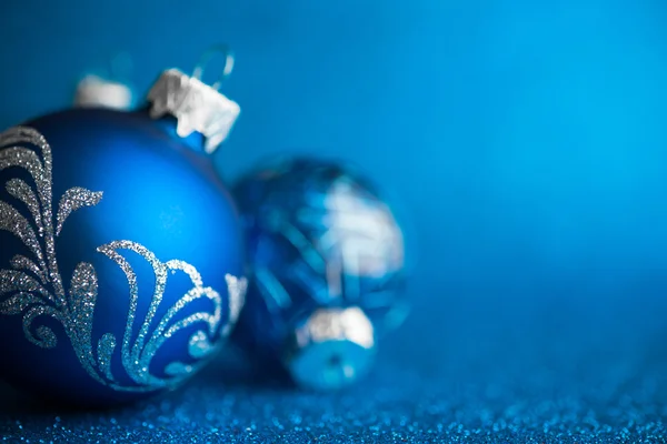 Blue xmas ornaments on dark blue glitter background. Merry christmas card. Winter holiday theme. Happy New Year.