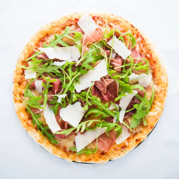 Pizza with prosciutto (parma ham), arugula (salad rocket) and parmesan top view. Italian cuisine.