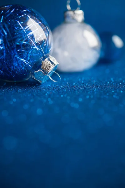 White and blue christmas ornaments on dark blue glitter background with space for text