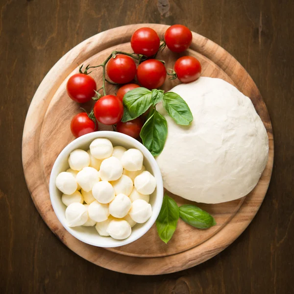 Ingredients for pizza margherita on wooden plate top view