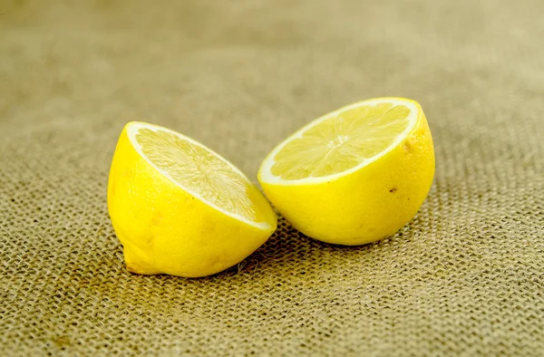 Bright yellow lemon cut in half against rustic textured hessian