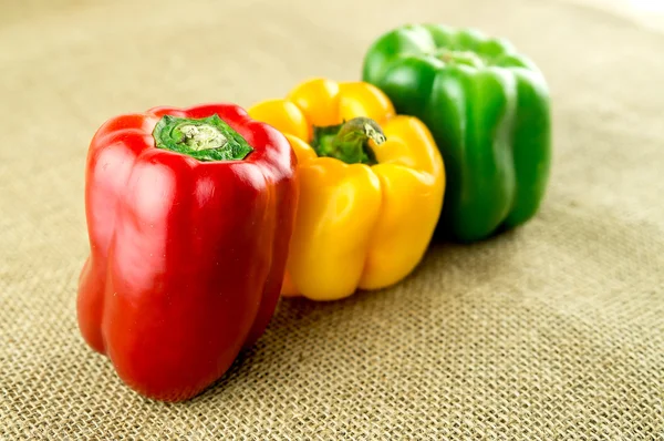 Delicious bell peppers on rustic burlap background
