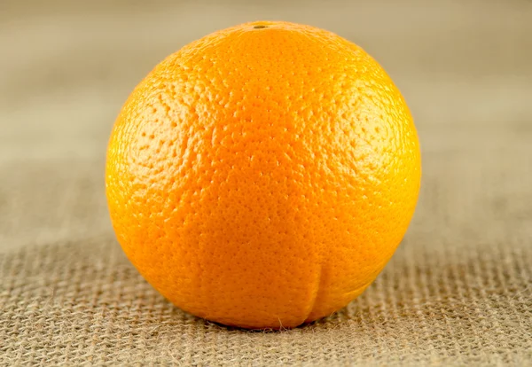 Macro closeup of organic ripe orange on hessian backdrop