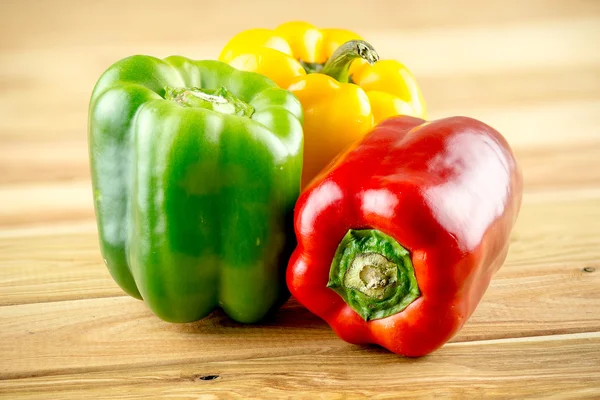 Red yellow and green peppers on wooden background