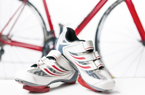 Cycling and sport Concept. Sport Cycling Shoes with Cleats and Covers On Against Red Professional Road Bike