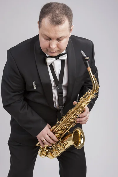 Caucasian Man in Suite with Saxophone. Posing Against White.