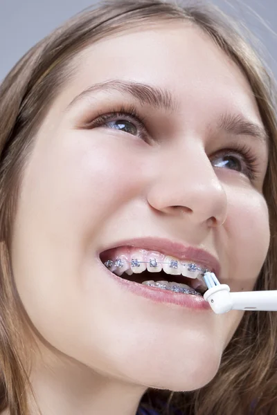 Dental Concept and Ideas.Extreme  Closeup Portrait of Caucasian Teenage Girl Brushing Teeth Brackets with Electric Toothbrush