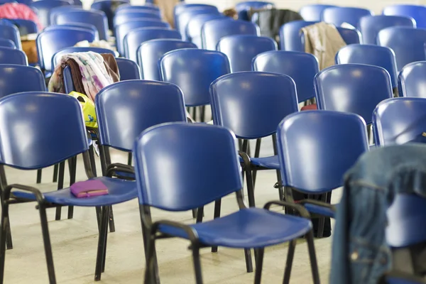 Closeup of Empty Chairs in Line with Workbooks Laid Upon It