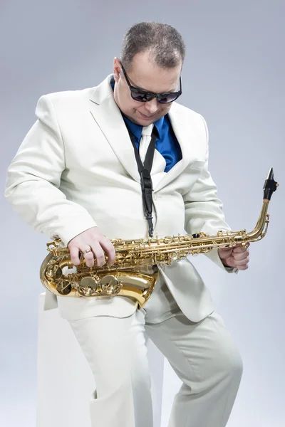Music Concept and Ideas. Handsome Caucasian Musician with Saxophone Posing in White Siut