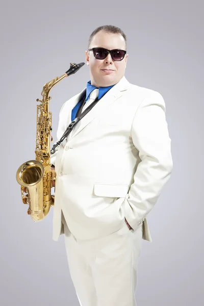 Handsome Smiling Male Saxo Player in Stylish White Suit and Sunglasses Posing Against White