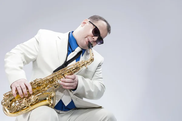 Portrait of Passionate Expressive Male Alto Saxophone Player in White Suit.