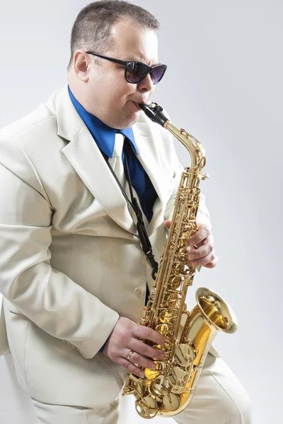 Expressive Stylish Caucasian Saxophone Player Performing in White Suit and Sunglasses in Studio