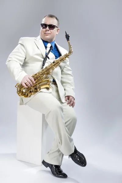 Full Length Portrait of Handsome Caucasian Musician With Alto Saxophone Posing In White Suit Against White Background