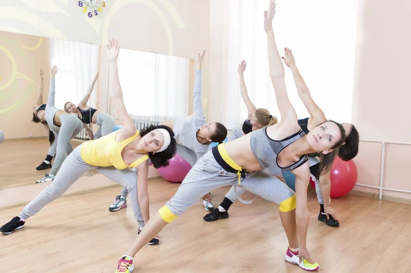 Sport Concepts. Group of Five Young Caucasian Females Making Stretching Exercises in Sport Venue.
