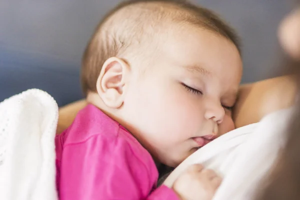 Little Cute Caucasian Infant Sleeping on Mothers Hands Indoors.