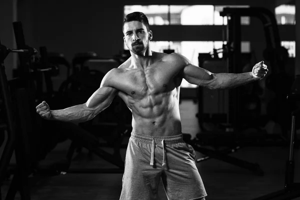 Muscular Man Flexing Muscles In Gym