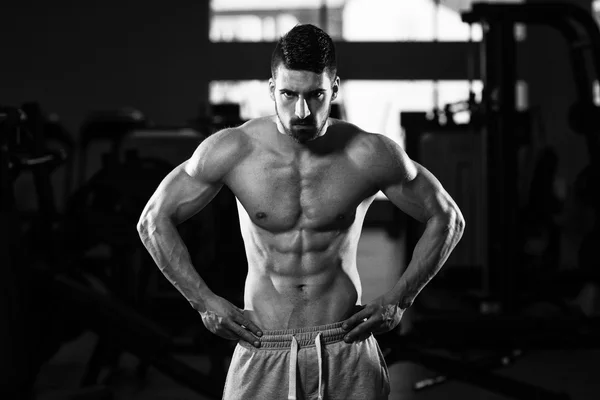 Muscular Man Flexing Muscles In Gym