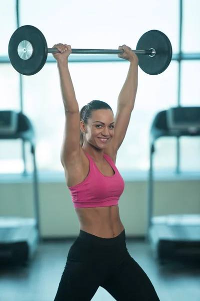 Fitness Woman Using Barbell Exercising Shoulders Inside Gym
