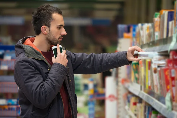 Man Using Mobile Phone While Shopping In Supermarket