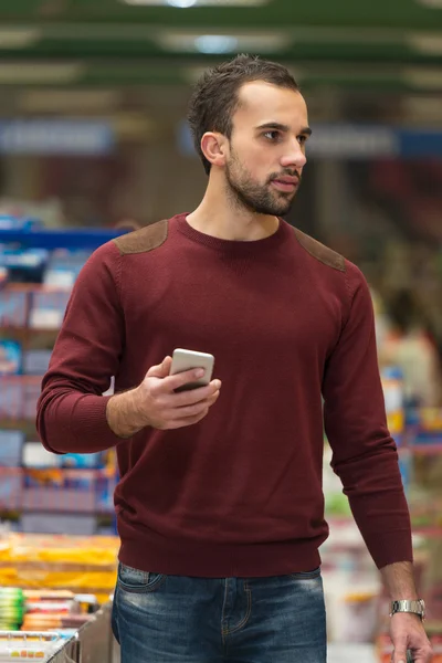 Man Using Mobile Phone While Shopping In Supermarket