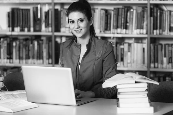 Happy Female Student Working With Laptop In Library