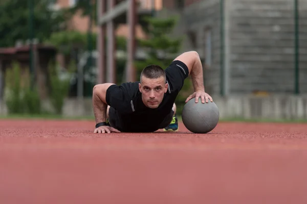 Young Man Exercising Push-Ups On Medicine Ball Outdoor