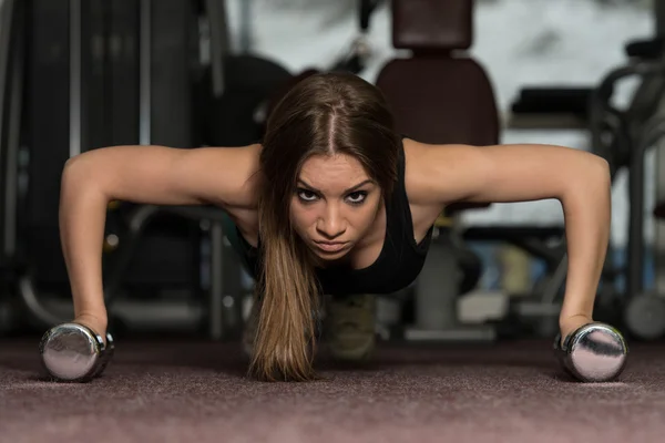 Young Woman Exercising Push Ups With Dumbbells