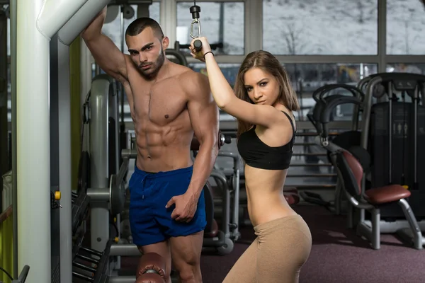 Young Couple Doing Exercise For Triceps On Machine