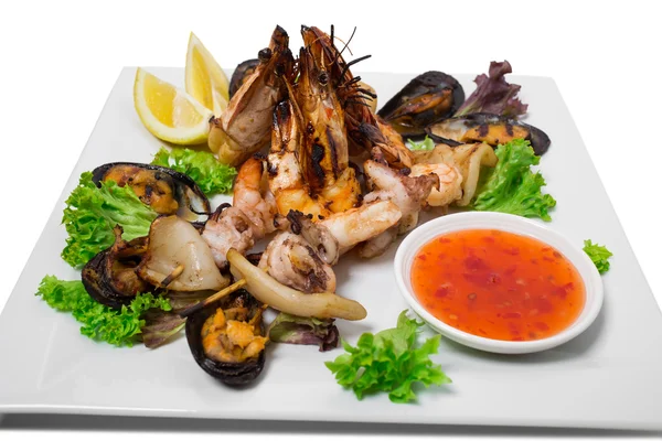 Grilled seafood platter with hot sauce.