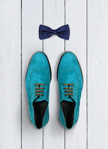 Male shoes and bow-tie on a white wooden background