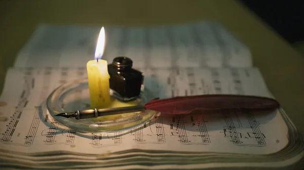 Feather and candle on a music book