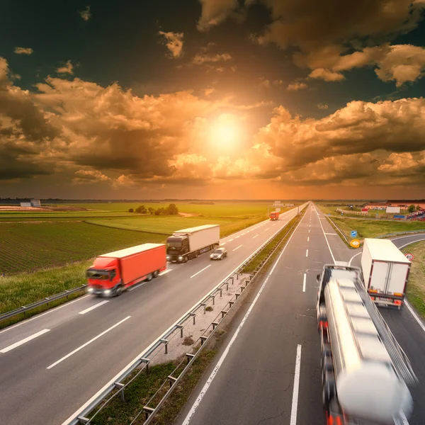 Driving trucks in motion blur on the highway at sunset