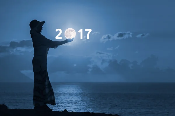 Woman holding moon in hands for upcoming 2017