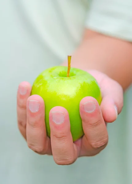 A person is handing green apple for you.