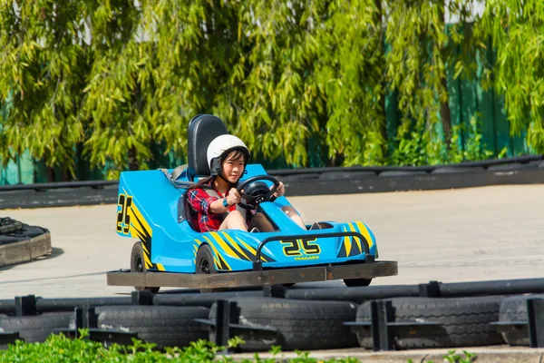Cute Asian Thai girl is driving Go-kart car with speed in a playground racing track. Go kart is a popular leisure motor sports.