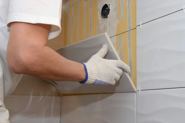 Construction work laying tile on the wall