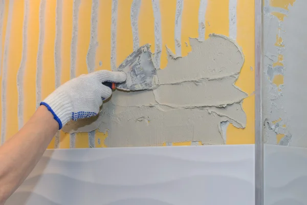 Construction work laying tile on the wall