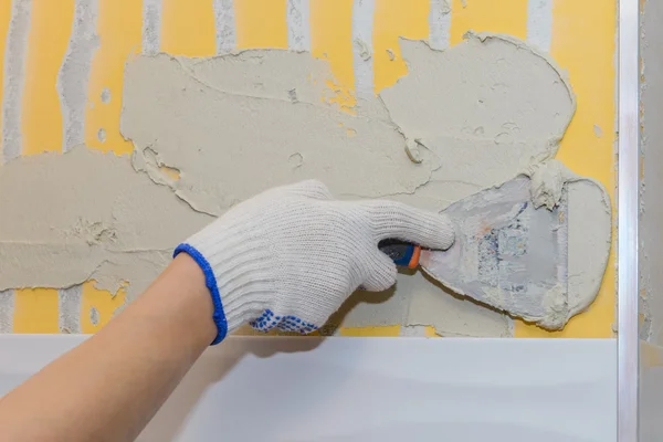 Construction work laying tile on the wall