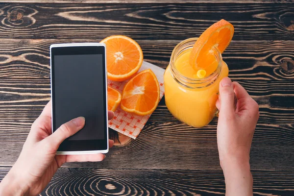 Woman Using Mobile Phone against Fruits Oranges. Technology Concept.