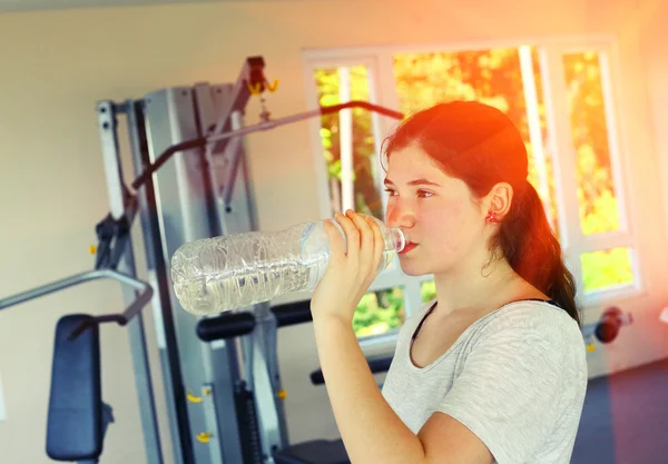 Teenager pretty girl in gym drink water