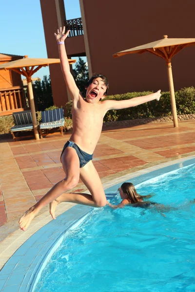 Preteen boy jump into the open air swimming pool
