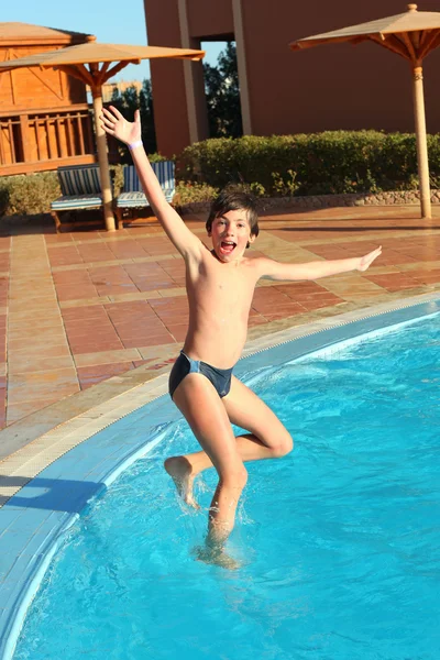 Preteen little boy jump into open air swimming poo