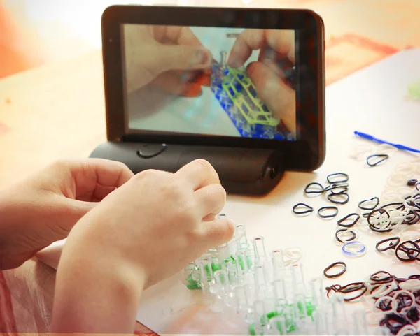 Hand make rainbow loom toy with online lesson on tablet computer
